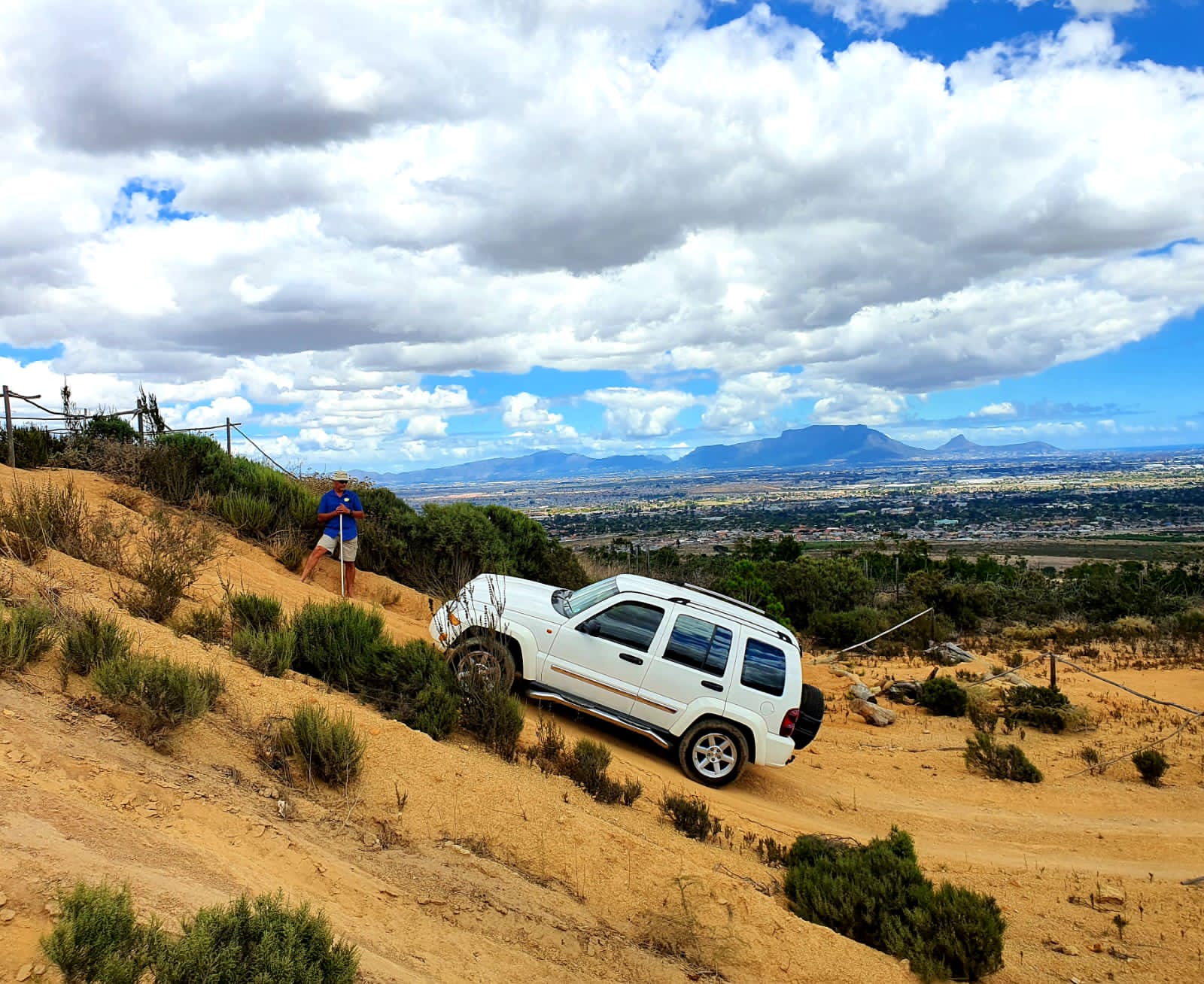 Jeep Liberty descending a steep slope with the instructor watching on, Table Mountain behind