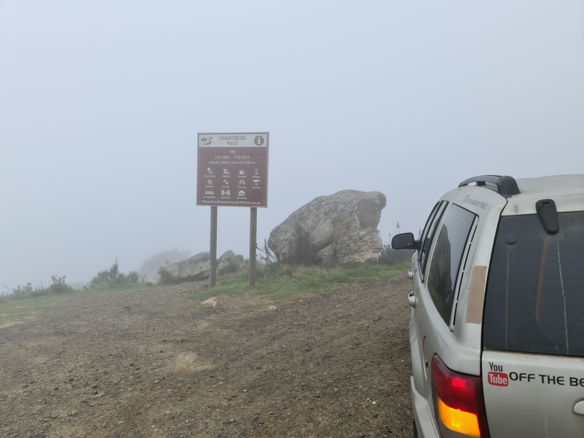 The summit — socked in cloud, the Swartberg Pass sign barely visible. No view. Worth it anyway.