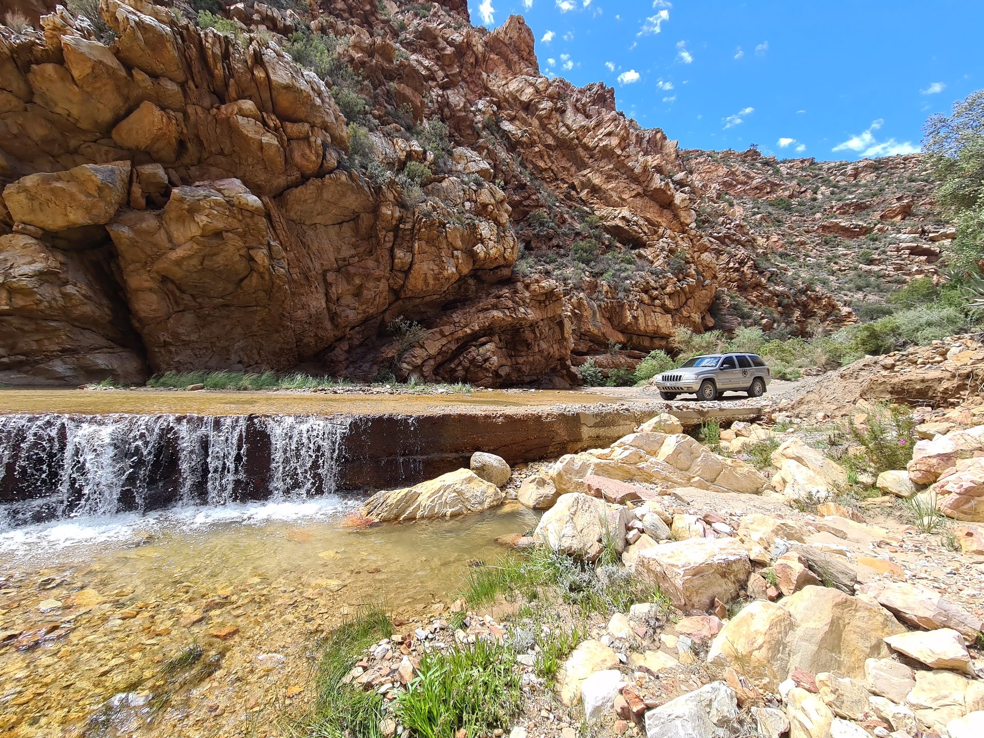 The weir crossing — the Jeep parked at the river ford, waterfall pouring over the ledge