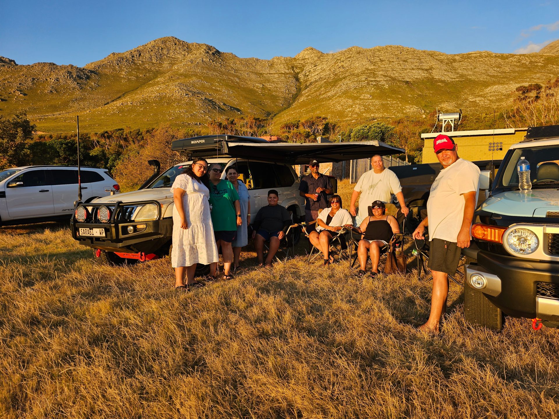 Friends gathered beside the vehicles in the golden evening light